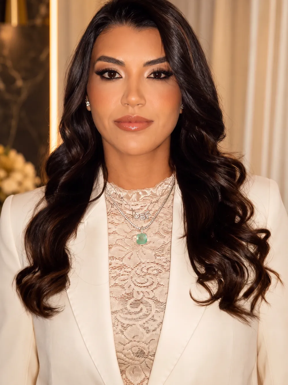Dra. Daniela Carvalho, de blazer off-white, em ambiente com luz quente lateral